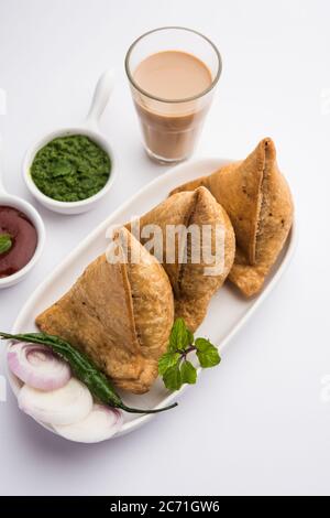 Samosa - Triangle shape fried / baked pastry with savoury filling, popular Indian Tea Time snacks, served with green chutney, tomato ketchup Stock Photo