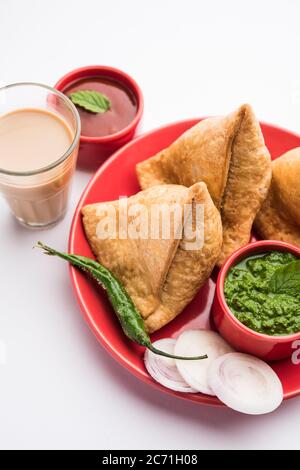 Samosa - Triangle shape fried / baked pastry with savoury filling, popular Indian Tea Time snacks, served with green chutney, tomato ketchup Stock Photo