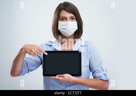 Woman wearing protective mask and holding tablet isolated over white background Stock Photo