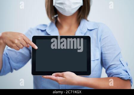 Woman wearing protective mask and holding tablet isolated over white background Stock Photo