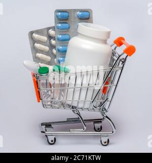 Shopping cart with full of medical pills or vitamins over light grey background Stock Photo