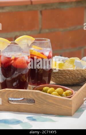 https://l450v.alamy.com/450v/2c71ky5/two-crystal-glasses-filled-with-red-wine-and-soda-with-ice-cubes-and-slices-of-lemon-typical-spanish-on-a-wooden-tray-with-a-plate-of-olives-and-a-bow-2c71ky5.jpg