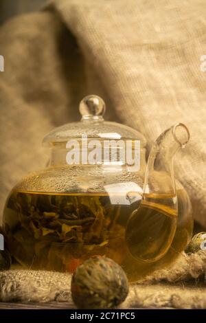 Flower tea brewed in a glass teapot on a background of homespun fabric with a rough texture. Close up Stock Photo