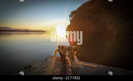 Sunrise sunset at the river 'Canal do estuário', between the citys of Guaruja and Bertioga in Brazil. Colorful and serene sunrise at a calm river. Sli Stock Photo