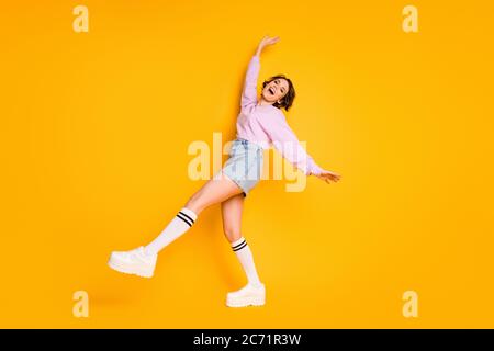 Full size photo of candid cute sweet youngster girl enjoy her spring summer rest relax raise legs hands wear good look jumper footwear isolated shine Stock Photo