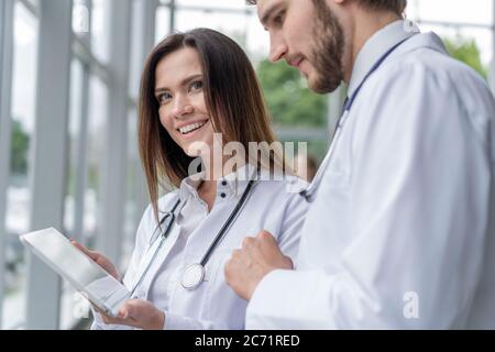Male doctor using digital tablet with female colleague in hospital, working together. Stock Photo
