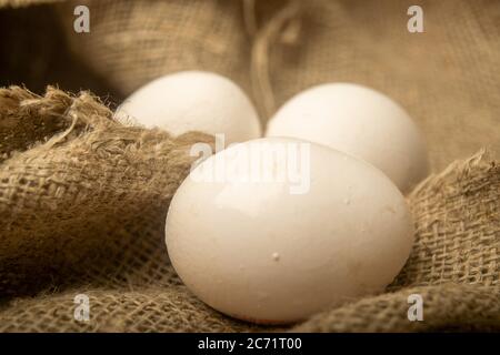 White chicken eggs on a background of homespun fabric with a rough texture. Close up Stock Photo