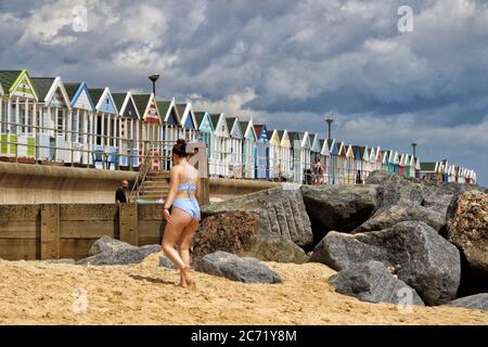 Southwold, UK. 12th July, 2020. A woman wearing a bikini walks along the shores of the beach.With the beaches in England now fully opened with only social distancing measures in force, people are taking the chance to visit some coastal resorts. Southwold is an English resort town full of an olde world charm and famous for its 300 brightly coloured beach huts. Plenty of people were out and about on the sandy beach and on the pier. Credit: SOPA Images Limited/Alamy Live News Stock Photo