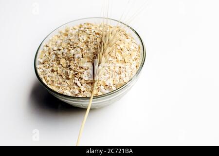Bowl full of oats. Porridge oats in cereal bowl on white background. A bowl of whole oats isolated on a white. Healthy Eating concept-Oat Flakes. Stock Photo