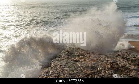 Sea waves hitting rocks in Nazare, Portugal Stock Photo