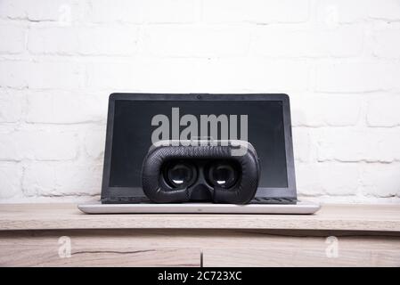 3d glasses and laptop on a wooden table against a brick wall Stock Photo