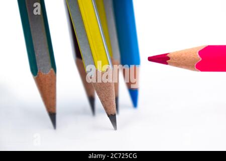 One red colored wood pencil crayon pointing at five different colored wood pencil crayons Stock Photo