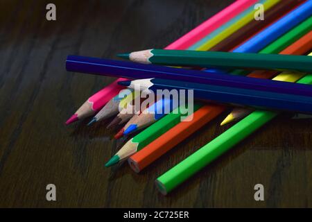 Pile of different colored wood pencil crayons placed in top of one another on a desk Stock Photo