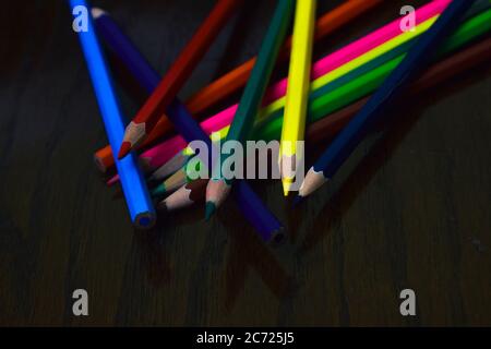 Stack of different colored wood pencil crayons placed in top of one another on a desk Stock Photo
