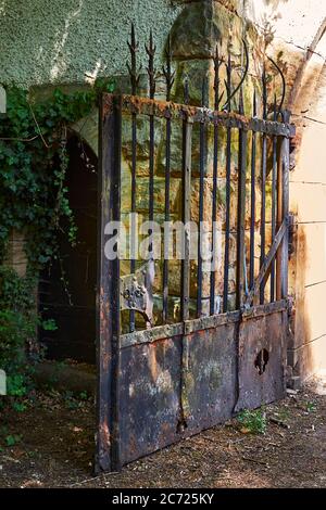 Access to a small old castle. In the center you can see a rusty wrought-iron gate. Stock Photo