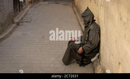 Fez, Morocco - April 2018: Anonymous poor beggar in the street of Fez, Morocco. Stock Photo