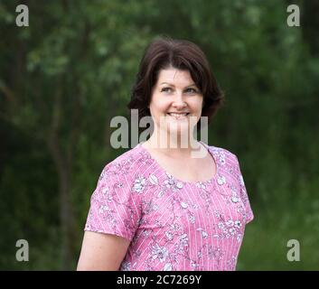 Middle-aged Woman in a pink dress on a summer forest background Stock Photo