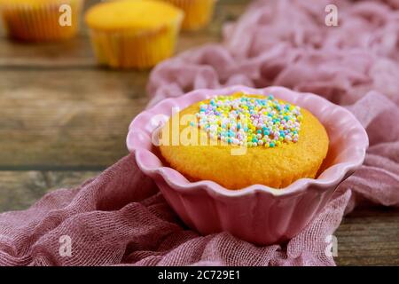 Cupcake in pink bowl with sugar sprinkles. Close up. Stock Photo