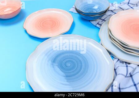 Varicolored ceramic plates and bowls on blue background Stock Photo