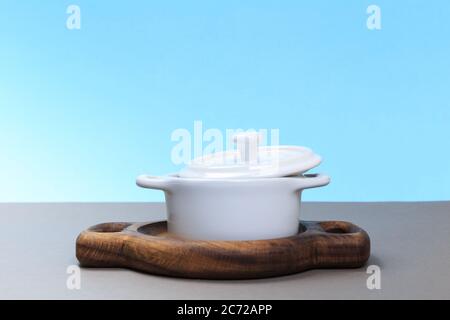 A new ceramic pan stands on a gray table and a blue background. Stock Photo