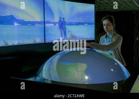 MOSCOW, RUSSIA - JUNE 05, 2019: Smart Expo. Woman using interactive model of Earth in dark room of multimedia museum, exhibition with low light Stock Photo