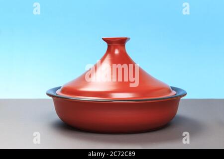 A new ceramic pan stands on a gray table and a blue background. Stock Photo