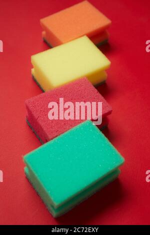 Close-up of colorful sponges for cleaning lying in a row isolated on red background Stock Photo