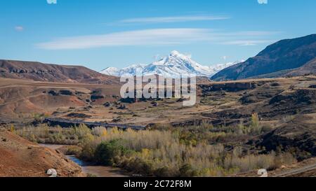 Erzincan, Turkey - August 2018: View of a valley with a train and railway with snow capped mountains and Firat river near Erzincan, Turkey Stock Photo