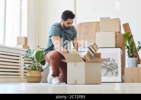Young man packing the books in cardboard boxes he moving the house Stock Photo