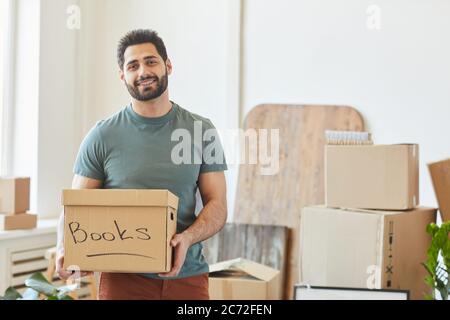 Portrait of bearded happy man holding box with books and smiling at camera Stock Photo