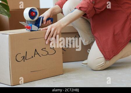 Close-up of woman packing signed boxes with adhesive tape during relocation Stock Photo