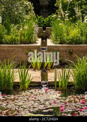Rill flowing into the rectangular lily pond of the Edwardian garden at RHS Harlow Carr. Harrogate, North Yorkshire, UK Stock Photo