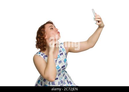 Portrait of a young redheaded overweight girl on a white background isolated, Pictured in profile, fooling around and taking a selfie Stock Photo