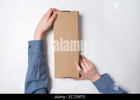 Craft paper box in children's hands on white background. Top view. Copy space Stock Photo