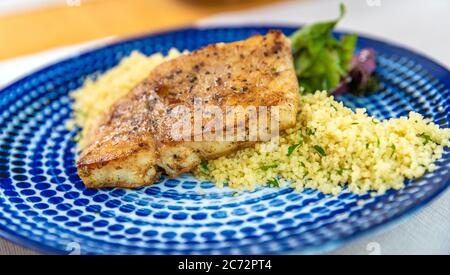 Roast pork with couscous on a plate, close-up