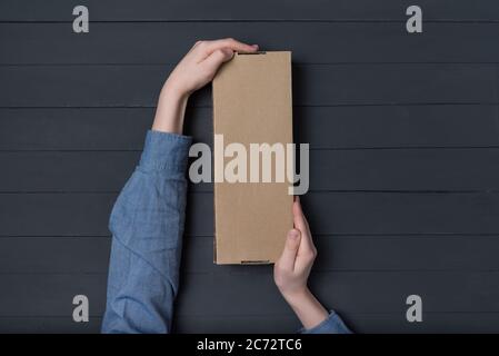 Craft paper box in children's hands on black background. Top view. Copy space Stock Photo