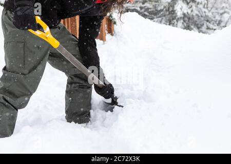 close up view of man using a shovel to shoveling the snow outdoor in the backyard during snowfall, Manual snow removal with copy space on the right. Stock Photo
