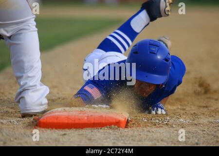 A baserunner scrambles back to first on an attempted pick-off in a tightly cropped photo. Stock Photo