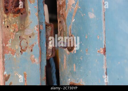 Old rusty blue door, open, close up key in lock  Stock Photo