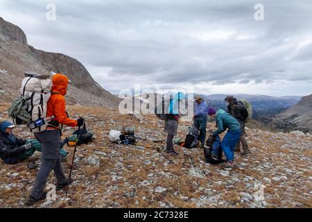 Backpackers put on rain gear as stormy weather approaches on a saddle below Europe Peak. Wind River Range, Wyoming Stock Photo