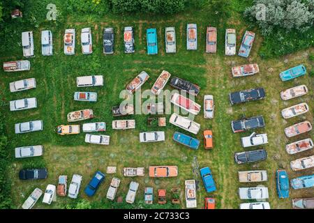Old retro rusty abandoned cars in green grass, aerial top view from drone above cemetery of vintage autos.
