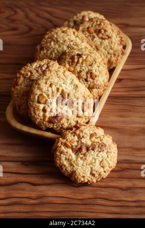 Oatmeal cookies with walnuts and raisins on bamboo plate standing on a wooden table Stock Photo
