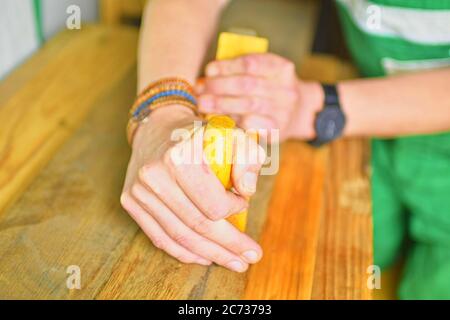 Carpenter working with plane on table in his workshop. Carpenter working with plane in a carpentry shop. Young carpenter wearing bracelets Stock Photo