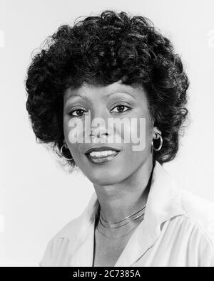 1970s PORTRAIT SMILING AFRICAN AMERICAN WOMAN WEARING HOOP EARRINGS GOLD CHAIN NECKLACE CURLY AFRO HAIRSTYLE LOOKING AT CAMERA - g8608 HAR001 HARS EXPRESSIONS B&W CONCERNED EYE CONTACT HAPPINESS HEAD AND SHOULDERS CHEERFUL AFRICAN-AMERICANS AFRICAN-AMERICAN HAIRSTYLE BLACK ETHNICITY CURLY PRIDE SMILES CONCEPTUAL JOYFUL STYLISH YOUNG ADULT WOMAN BLACK AND WHITE HAR001 OLD FASHIONED AFRICAN AMERICANS Stock Photo