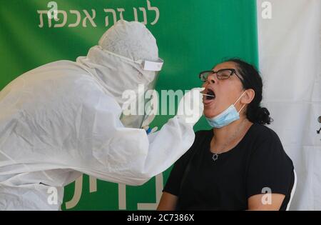 Lod, Israel. 13th July, 2020. A medical worker collects a swab from a woman for a COVID-19 test in Lod, central Israel, on July 13, 2020. Israel's Ministry of Health has reported 1,962 new coronavirus cases on Monday, bringing the total cases to 40,632. Credit: Gil Cohen Magen/Xinhua/Alamy Live News Stock Photo