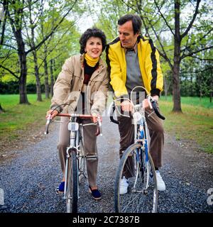 1980s MATURE COUPLE HUSBAND AND WIFE RIDING BICYCLES IN PARK IN EARLY SPRING WOMAN LEANING SHOULDER TO SHOULDER TO MAN ROMANCE  - kb18124 PHT001 HARS PAIR ROMANCE BEAUTY SUBURBAN SPRING COLOR RELATIONSHIP EXPRESSION OLD TIME NOSTALGIA LEANING OLD FASHION 1 FITNESS SILLY FACIAL STYLE HEALTHY COMIC STRONG LIFESTYLE SATISFACTION FEMALES MARRIED BIKING RURAL SPOUSE HUSBANDS HEALTHINESS COPY SPACE FRIENDSHIP FULL-LENGTH LADIES PHYSICAL FITNESS PERSONS CARING MALES BICYCLES EXPRESSIONS MIDDLE-AGED PARTNER BIKES MIDDLE-AGED MAN BRUNETTE ACTIVITY HUMOROUS HAPPINESS PHYSICAL MIDDLE-AGED WOMAN EARLY Stock Photo