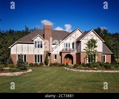 1990s SPACIOUS BRICK TWO STORY TUDOR STYLE HOUSE WITH ARCHED FRONT ENTRANCE TALL CHIMNEY AND NEW MOWN LAWN - kb29942 TEU001 HARS ARCHED PRIDE HOMES REAL ESTATE CONCEPTUAL STRUCTURES RESIDENCE STYLISH EDIFICE SPACIOUS CHIMNEY OLD FASHIONED Stock Photo