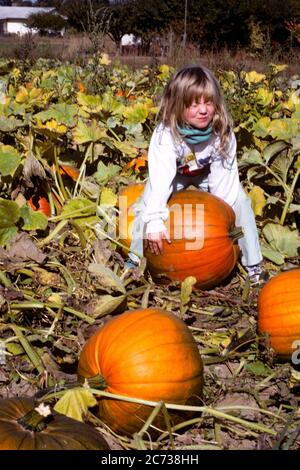 Girl trying to lift a pumpkin in a pumpkin patch Stock Photo - Alamy