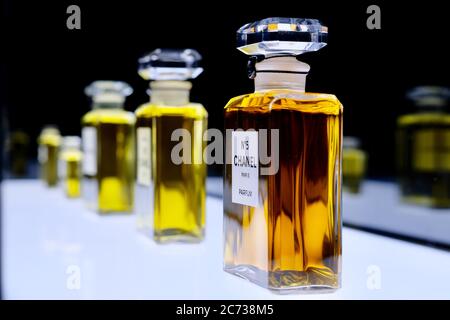 Close up bottles of famous NO.5 Chanel perfume on white shiny board. Perspective view of number five Chanel parfum collection. Stock Photo