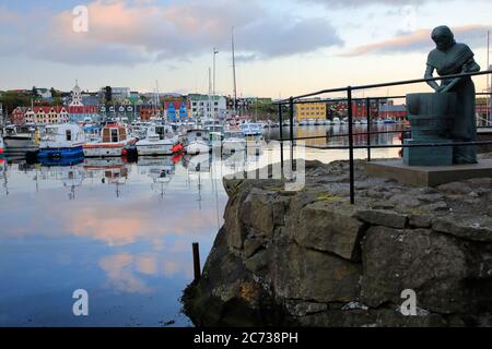 Torshavn harbor at dusk with the female statue in honor of the processing of cod in foreground.Torshavn. Streyomy. Faroe Islands.Territory of Denmark Stock Photo